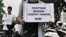 Anggota Koalisi Pejalan kaki menyelipkan selebaran di salah satu sepeda motor yang parkir di trotoar depan GBK, Jakarta, Minggu (9/12). Aksi tersebut dalam rangka menyadarkan masyarakat tentang pelanggaran parkir liar. (Merdeka.com/Iqbal S. Nugroho)