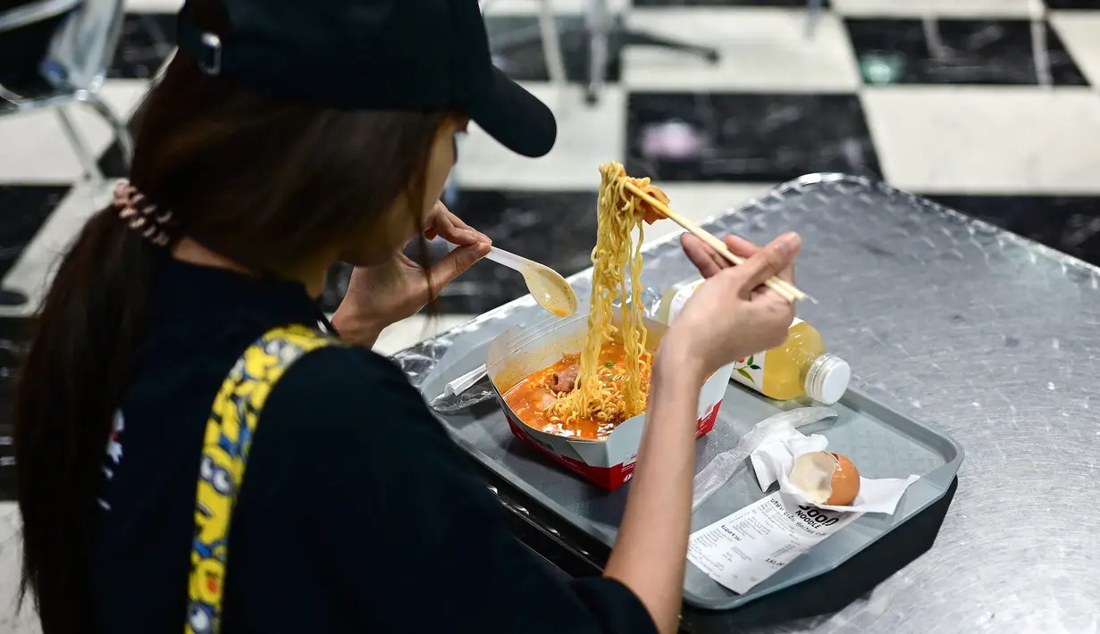 Seorang wanita makan mie instan untuk makan siang di toko Good Noodle yang menjual berbagai macam mie instan dari seluruh Asia, di Bangkok (25/8/2022). Thailand akan menaikkan harga mie instan Thailand, kata departemen perdagangan 24 Agustus menandai kenaikan harga pertama pada kebutuhan pokok harian dalam 14 tahun. (AFP/Vatsyayana)