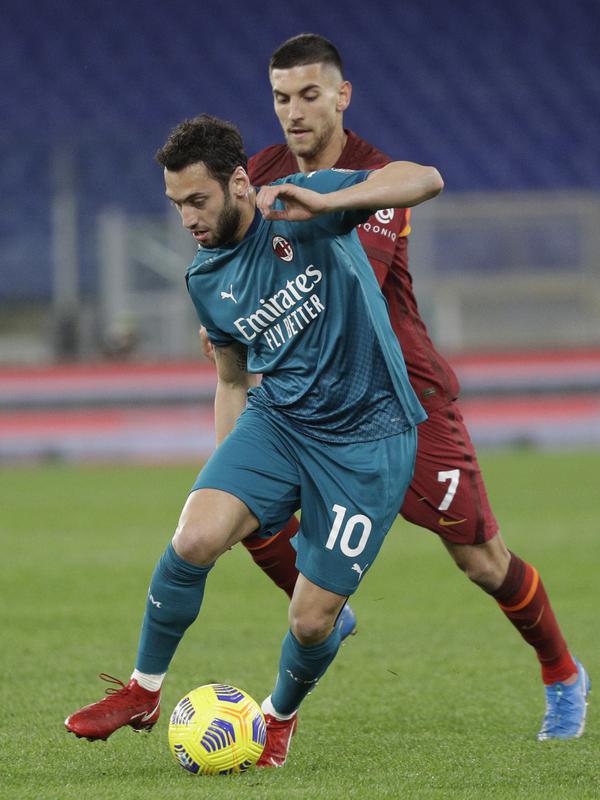 Gelandang AC Milan, Hakan Calhanoglu mengontrol bola dari kawalan gelandang AS Roma, Lorenzo Pellegrini pada pertandingan lanjutan Liga Serie A Italia di stadion Olimpiade, Italia,Senin (1/3/2021). Saat ini AC MIlan mengemas 52 poin terpaut 4 poin dari Inter Milan. (AP Photo/Gregorio Borgia)