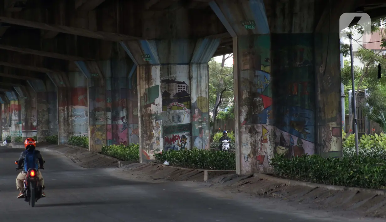 Pengendara motor melintasi sisi tiang penyangga Jalan Tol Pelabuhan Lingkar Dalam Jakarta di Jalan Ancol Timur, Jakarta, Selasa (16/6/2020). Seni mural yang dulu menghiasi tiang-tiang jalan tol di kawasan tersebut kini terlihat kusam dan berdebu. (Liputan6.com/Helmi Fithriansyah)