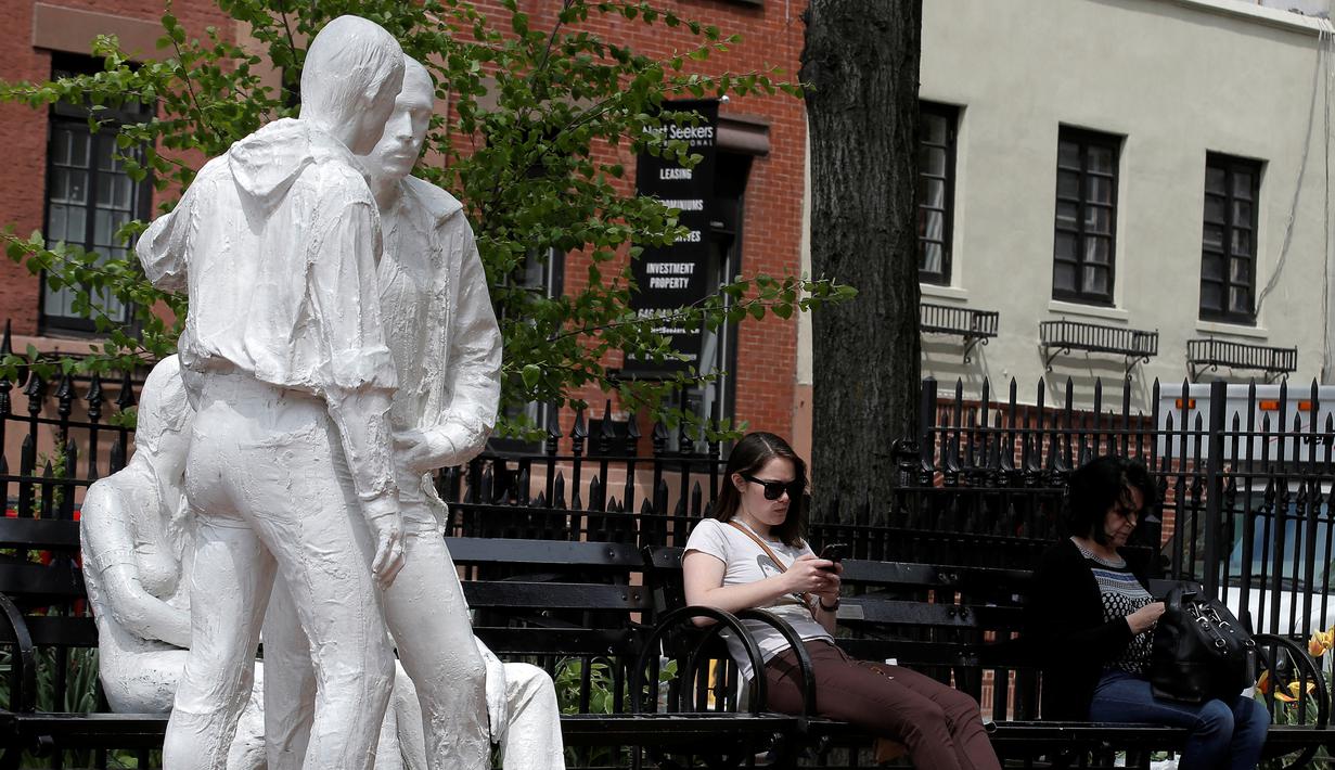 Dua perempuan duduk di dekat patung yang disebut 'Gay Liberation' di Christopher Park, Greenwich Village New York City, AS, (9/5). Patung ini dibuat untuk memperingati peristiwa pembebasan gay dan lesbian di Amerika Serikat. (REUTERS / Brendan McDermid)
