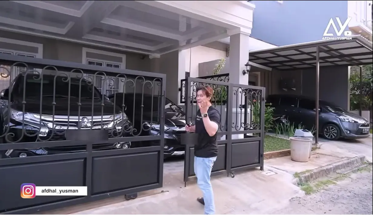 Afdal Yusman artis yang kini jadi Youtuber itu berkesempatan menyambangi rumah baru Angga yang ditempati sekitar tiga bulan. Pagar besi hitam dan dua mobil terparkir di garasi. [Youtube/Afdhal Yusman]