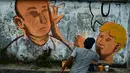 Seniman melukis mural yang menggambarkan senator Australia, Fraser Anning dipukul kepalanya menggunakan sebutir telur oleh William Conolly, di Banda Aceh, Aceh, Kamis (21/3/2019). (CHAIDEER MAHYUDDIN/AFP)