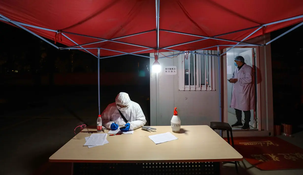 Para pekerja berpakaian pelindung duduk di luar hotel yang digunakan dalam isolasi medis virus corona di Wuhan, Provinsi Hubei, China, Senin (3/2/2020). Dokter pengungkap virus corona, dr Li Wenliang, sempat dituduh menyebarkan informasi palsu. (Chinatopix via AP)