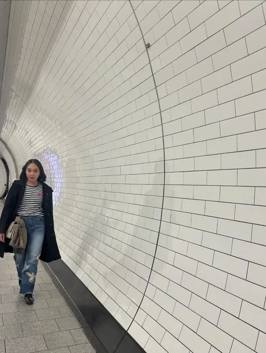 Dewi Gita diketahui sedang berlibur bersama sang suami di London. Gaya awet muda Dewi Gita mengenakan kaus bercorak garis ditumpuk dengan long coat hitam, dan dipadu celana jeans. [Foto: Instagram/dewigita01]