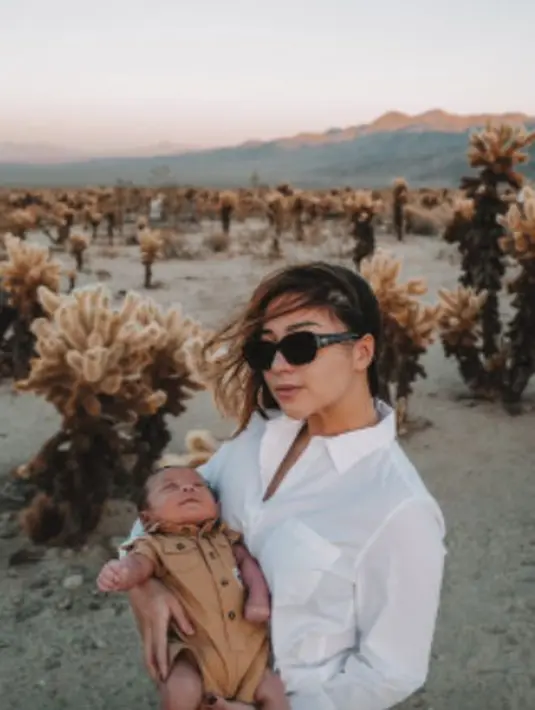 <p>Berfoto di tengah hamparan Joshua Tree, Baby Issa nampak tertidur sambil tersenyum di pelukan sang ibu. Sementara itu, Nikita Willy tampil keren menggunakan kacamata hitam. (instagram/indpriw)</p>
