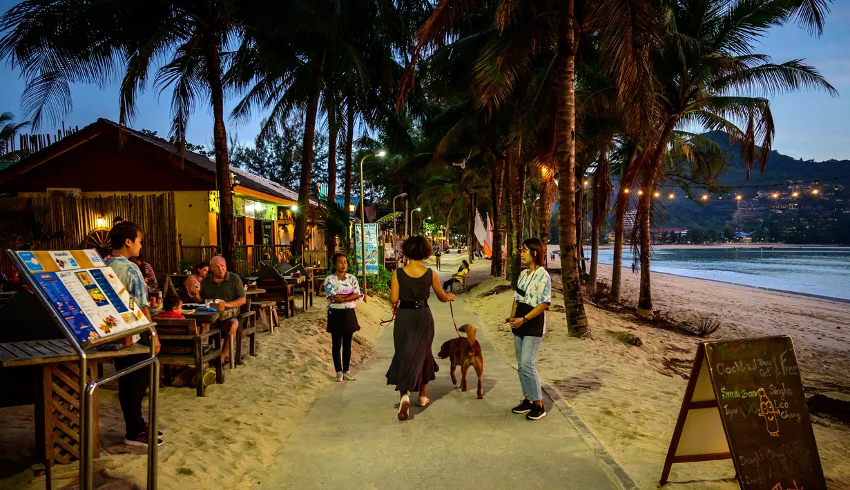 Karyawan restoran mengundang orang yang lewat saat para turis memanfaatkan program "Kotak Pasir Phuket" untuk pengunjung yang divaksinasi penuh terhadap virus corona Covid-19 di pulau Phuket Thailand (25/10/2021). (AFP/Mladen Antonov)