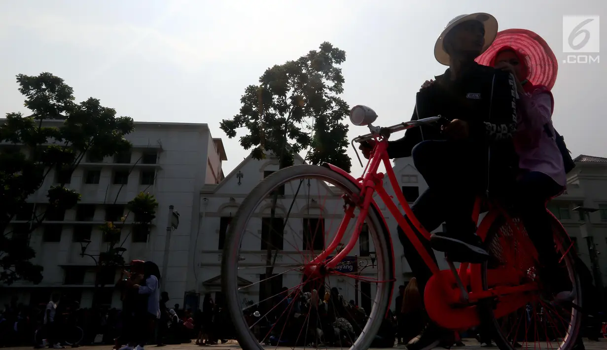 Pengunjung bersepeda mengelilingi kawasan Kota Tua, Jakarta, Selasa (20/11). Libur Maulid Nabi 2018 dimanfaatkan warga untuk berwisata di sejumlah lokasi, Salah satu yang ramai dikunjungi yakni Kota Tua. (Liputan6.com/Johan Tallo)