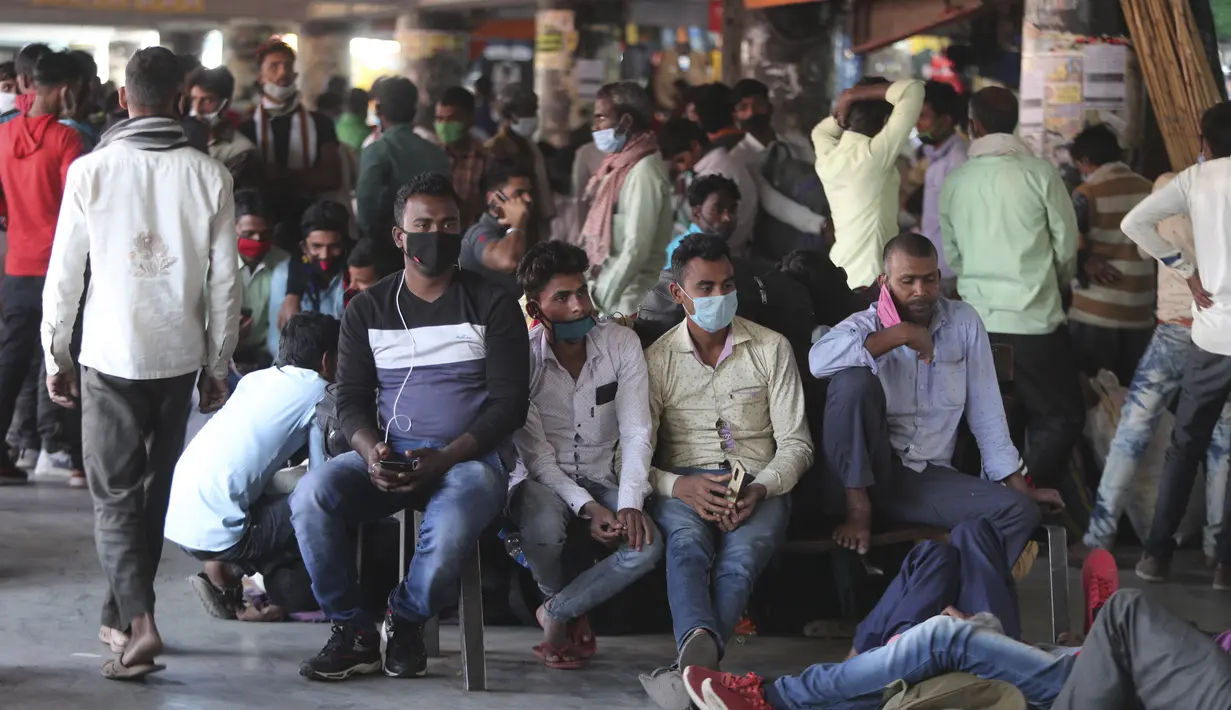 Buruh migran yang memakai masker sebagai antisipasi terhadap virus corona menunggu pengangkutan di terminal bus di Jammu, India (26/3/2021). Sejauh ini hanya 44 juta yang telah divaksinasi, 7,4 juta di antaranya sebagian. (AP Photo/Channi Anand)