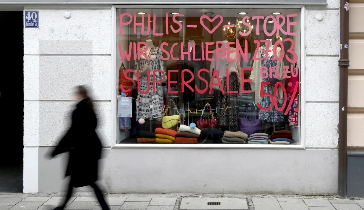 Seorang wanita melewati jendela toko yang bertuliskan 'Kami akan tutup pada 27 Maret' di Munich, Jerman, Selasa (23/3/2021). Jerman memperpanjang tindakan pengunciannya sebulan lagi. (AP Photo/Matthias Schrader)