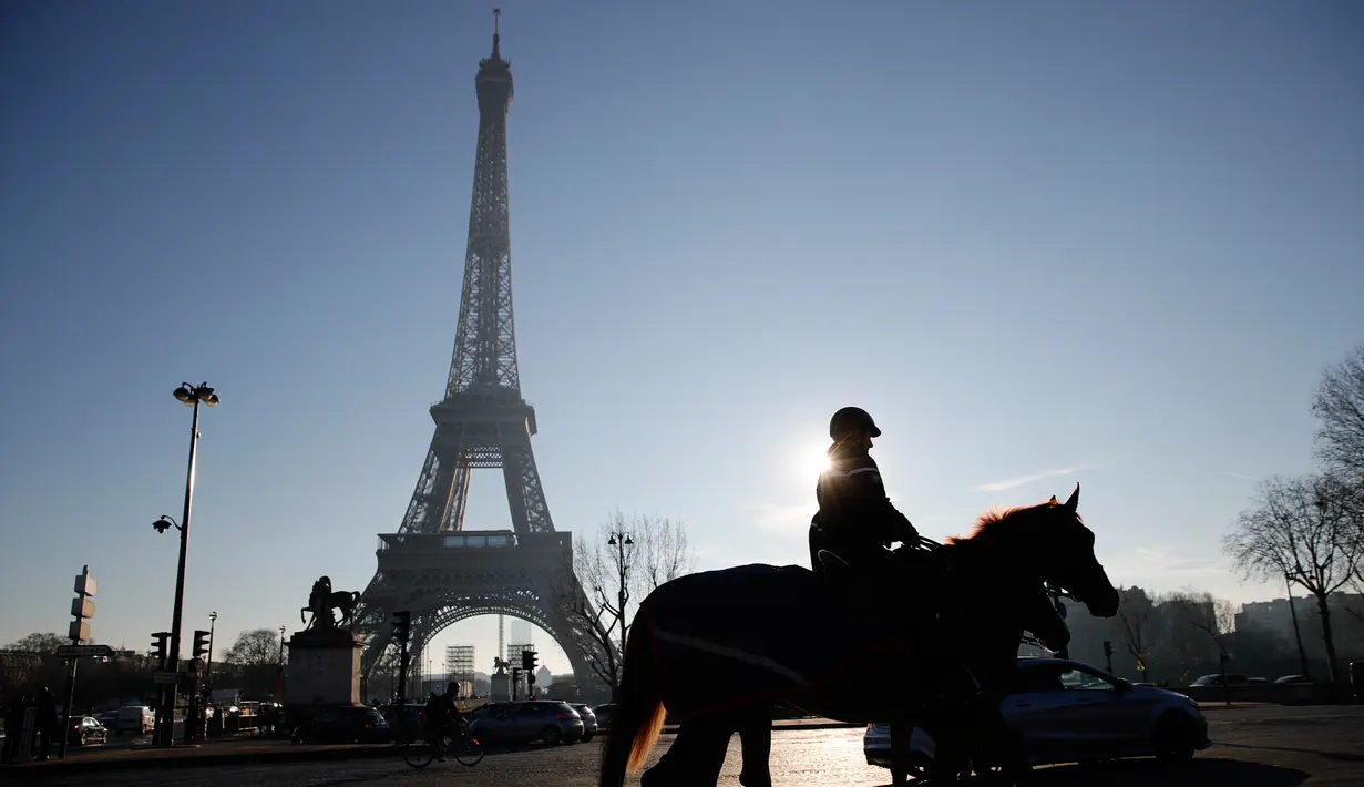 Seorang petugas polisi berpatroli di dekat Menara Eiffel di Paris,  Senin (30/12/2019). Pemerintah Prancis akan mengerahkan 100.000 petugas polisi untuk mengamankan ruang publik pada perayaan malam Tahun Baru di tengah aksi mogok yang sedang berlangsung. (AP/Christophe Ena)