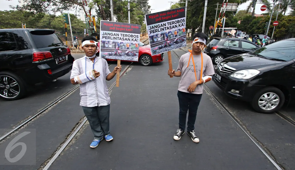 Komunitas Indonesian Railway Preservation Society menggelar spanduk imbauan di perlintasan kereta api, Menteng, Jakarta, Kamis (15/10). Kampanye itu guna menyadarkan masyarakat akan bahaya menerobos perlintasan kereta api. (Liputan6.com/Immanuel Antonius)