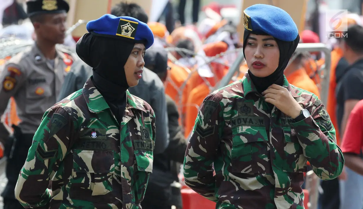 Dua aparat TNI wanita berjaga saat Hari Buruh Sedunia di depan Istana Negara, Jakarta, Selasa (1/5). Memperingati Hari Buruh 2018, ribuan buruh mulai memadati Istana Kepresidenan, Jakarta Pusat. (Liputan6.com/Johan Tallo)