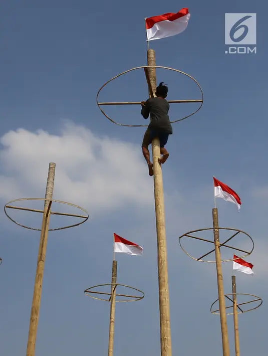 Pekerja memasang bendera Merah Putih pada pohon pinang untuk acara panjat pinang kolosal di kawasan Ancol, Jakarta, Kamis (15/8/2019). Ancol Taman Impian memasang sebanyak 174 batang pohon pinang untuk meriahkan Hari Kemerdekaan dengan tema " Pesta Manusia Merdeka". (Liputan6.com/Herman Zakharia)
