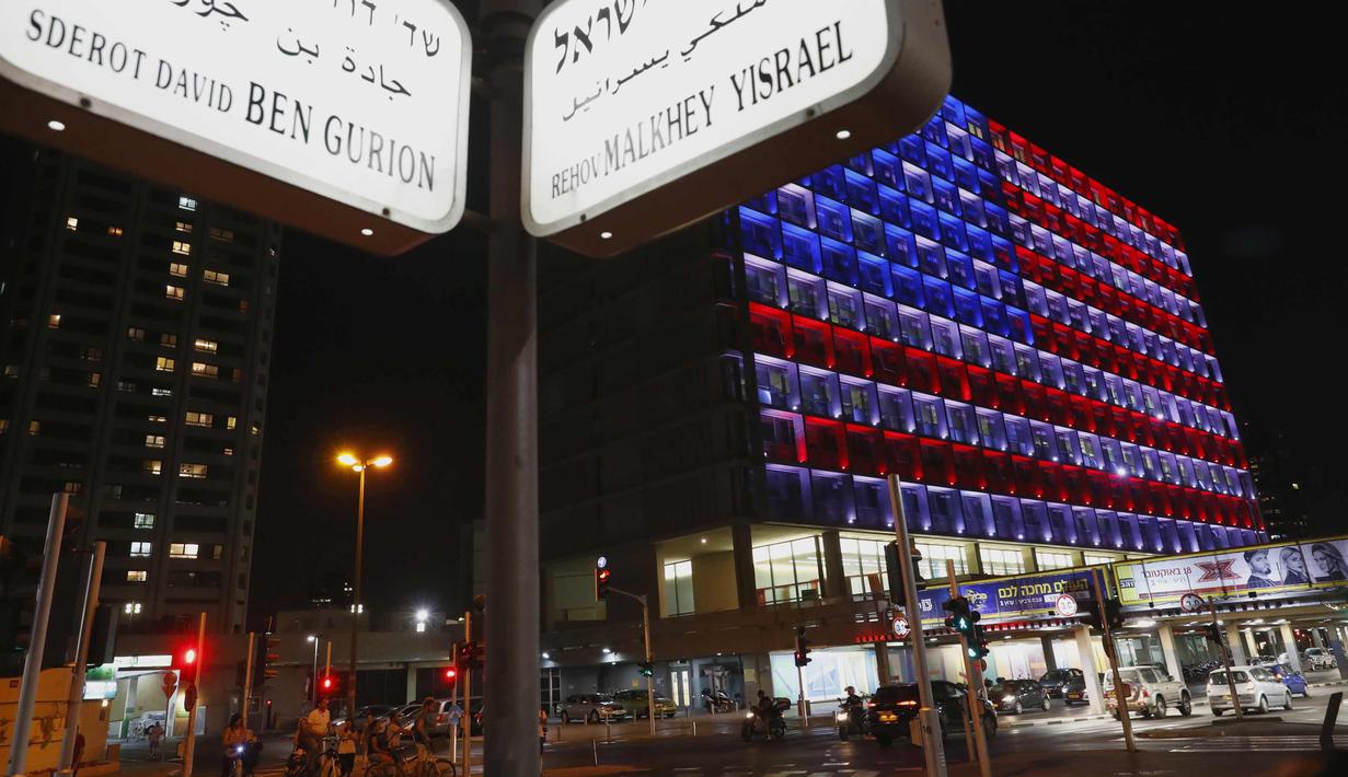 Suasana di dekat balai kota Tel Aviv yang dihiasi warna bendera AS untuk menghormati korban penembakan brutal di Las Vegas di Rabin Square, Tel Aviv (2/10). Menurut laporan, pelaku Stephen Paddock bunuh diri di lokasi kejadian. (AFP Photo/Jack Guez)