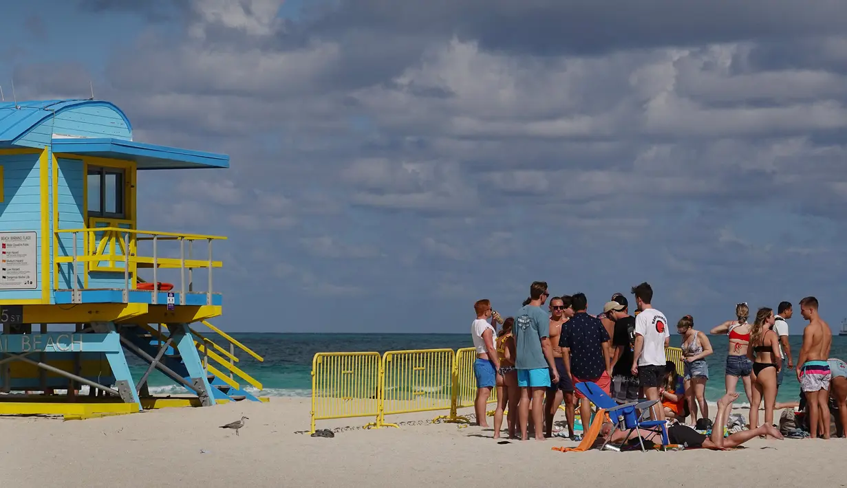 Orang-orang bersenang-senang di pantai di Miami, Florida pada Selasa (16/3/2021). Mahasiswa telah tiba di daerah Florida Selatan untuk liburan musim semi tahunan. Para pejabat kota prihatin dengan kerumunan liburan musim semi saat pandemi COVID-19 terus berlanjut. (Joe Raedle/Getty Images/AFP)