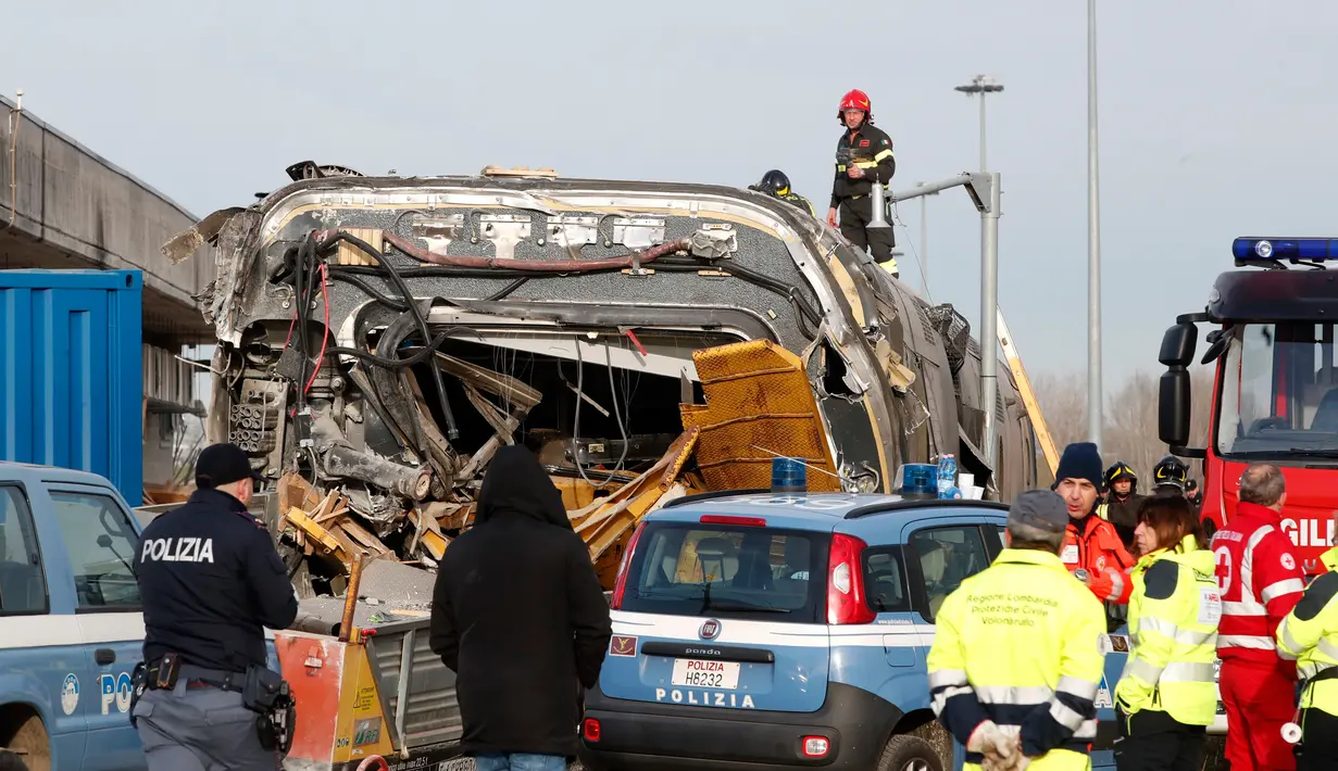 Petugas pemadam kebakaran memeriksa gerbong kereta yang tergelincir di dekat Lodi, Italia utara, Kamis (6/2/2020). Gambar yang beredar menunjukkan masinis terlempar keluar dari gerbong kereta pada sudut 45 derajat. (AP/Antonio Calanni)