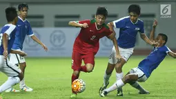 Penyerang Timnas Indonesia U-16, Rendi Juliansyah (tengah) mencoba melewati kawalan pemain Singapura U-16 saat laga persahabatan di Stadion Wibawa Mukti, Kab Bekasi, Kamis (8/6). Indonesia U-16 menang telak 4-0. (Liputan6.com/Helmi Fithriansyah)
