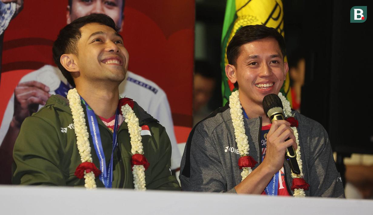<p>Juara ganda putra All England 2024, Muhammad Rian Ardianto (kanan) didampingi pasangannya, Fajar Alfian berbicara saat acara penyambutan para juara All England 2024 di Terminal 3 Bandara Soekarno Hatta, Tangerang, Banten, Senin (18/3/2024) malam WIB. (Bola.com/M Iqbal Ichsan)</p>