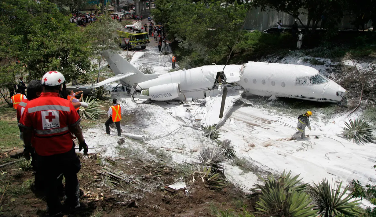 Sebuah pesawat jet pribadi Gulfstream G200 tertutup busa yang disemprotkan petugas pemadam kebakaran setelah tergelincir di Bandara Tegucigalpa, Honduras, Selasa (22/5). Sedikitnya 6 dilaporkan terluka dalam insiden tersebut. (AP/Fernando Antonio)