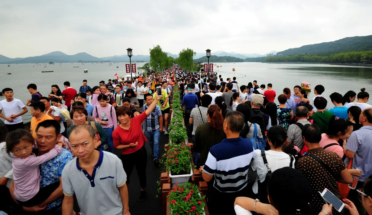 Pengunjung menunggu hantaman gelombang di tepi Sungai Qiantang di Hangzhou, provinsi Zhejiang, Tiongkok, 4 Oktober 2016. Hantaman gelombang ini menjadi daya tarik tersendiri bagi wisatawan. (REUTERS)