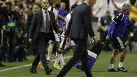 Pelatih Rayo Vallecano Paco Jemez mencoba menghampiri pelatih Real Madrid Zinedine Zidane yang tertunduk lesu usai timnya kalah 0-1 dalam laanjutan Liga Spanyol di Estadio de Vallecas, Senin (29/4/2019) dini hari WIB. (AP Photo/Paul White)