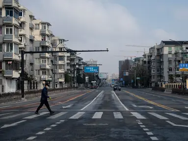 Pria bermasker menyeberangi jalanan yang sepi dekat kantor pusat Alibaba di Kota Hangzhou, Provinsi Zhejiang, China, Rabu (5/2/2020). Pemerintah Hangzhou memberlakukan pembatasan pergerakan bagi warganya menyusul mewabahnya virus corona. (NOEL CELIS/AFP)