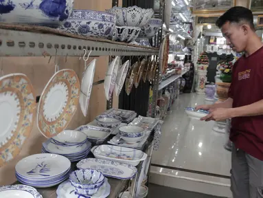 Pembeli melihat produk keramik yang dijual di kios kerajinan keramik kawasan Tanjung Priuk, Jakarta Utara, Kamis (23/9/2021). Pedagang mengaku pasokan keramik menurun hingga 70 persen seiring dangan pembatasan produksi pabrik akibat perpanjangan PPKM. (Liputan6.com/Herman Zakharia)