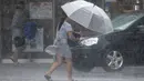 Seorang wanita Taiwan mengenakan payung berjalan melawan hembusan angin kencang yang ditimbulkan oleh topan Lekima di Taipei, Taiwan, Jumat (9/8/2019). Topan Lekima saat ini tengah menghantam Taiwan, membawa angin ribut dengan kecepatan 190 km/jam. (AP Photo / Chiang Ying-ying)