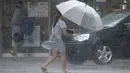Seorang wanita Taiwan mengenakan payung berjalan melawan hembusan angin kencang yang ditimbulkan oleh topan Lekima di Taipei, Taiwan, Jumat (9/8/2019). Topan Lekima saat ini tengah menghantam Taiwan, membawa angin ribut dengan kecepatan 190 km/jam. (AP Photo / Chiang Ying-ying)