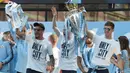 Pemain Manchester City, Kyle Walker, Kevin De Bruyne dan John Stones mengangkat trofi saat melakukan parade juara Premier League di Manchester, Senin (14/5/2018). The Citizens menjadi tim terbaik dengan raihan 100 poin. (AFP/Paul Ellis)