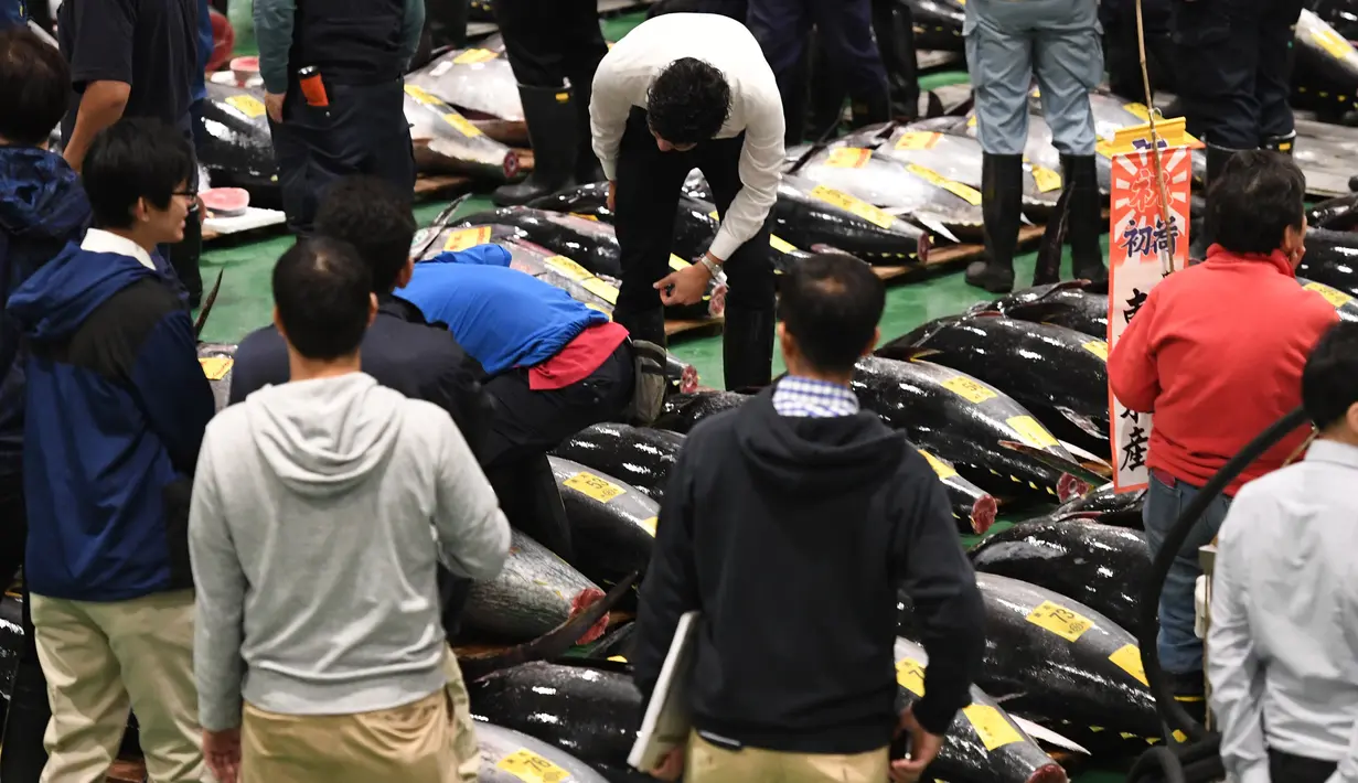 Pembeli, pekerja dan juru lelang menghadiri lelang tuna pada hari pertama pembukaan pasar ikan Toyosu di Tokyo, Kamis (11/9). Pasar ikan Toyosu menggantikan pasar ikan legendaris yang sudah mendunia, Pasar Tsukiji. (Toshifumi KITAMURA/AFP)