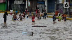 Anak-anak bermain air saat banjir menggenangi Jalan Jatinegara Barat, Jakarta, Kamis (2/1/2020). Hujan yang terjadi kemarin malam membuat Kali Ciliwung meluap ke jalan. (merdeka.com/Imam Buhori)