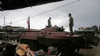 Dua tentara Filipina berdiri diatas tank usai menguasai kota Marawi dari tentara militan, Filipina (17/10). Duterte mendeklarasikan Kota Marawi telah terbebas dari kelompok militan Maute yang berafiliasi dengan ISIS. (AP Photo/Bullit Marquez)