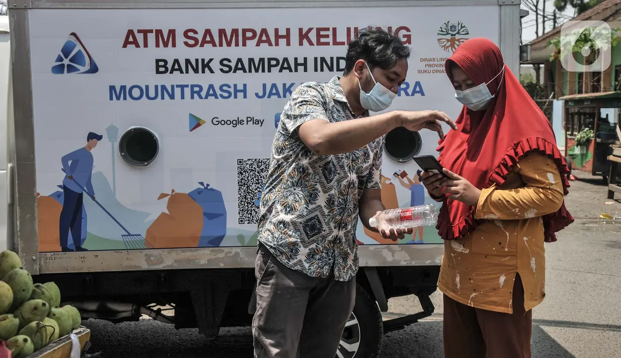 Petugas mendampingi warga saat memindai sampah botol melalui aplikasi smartphone sebelum ditabung ke ATM Sampah Keliling di kawasan Semper Barat, Cilincing, Jakarta Utara, Selasa (12/10/2021). (merdeka.com/Iqbal S. Nugroho)