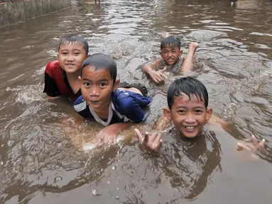 Sejumlah anak di kawasan Kemang Utara memanfaatkan banjir untuk bermain, Jakarta, Rabu (20/7). Akibat intensitas hujan deras yang mengguyur Jakarta, sejumlah ruas jalan tergenang air. (Liputan6.com/Yoppy Renato)