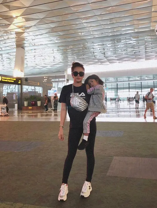 Selanjutnya, gaya Olla saat menggendong buah hatinya ini juga keren banget. Ia hanya mengenakan kaus dan celaana hitam yang dipadukan sneakers putih dan kacamata hitsnya. (Instagram/ollaramlanaufar)