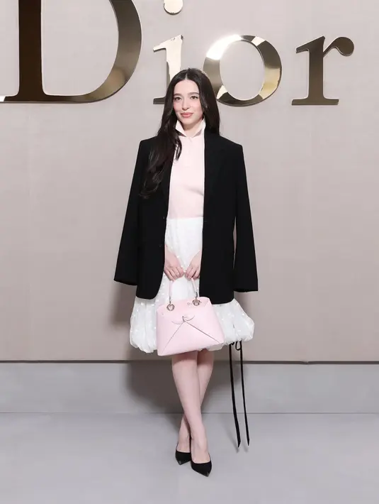 Mikey Madison kenakan jaket Dior hitam yang lapisi atasan sutra pink dan rok tulle putih. Siluet tas terbaru Dior warna pink pastel lengkapi tampilan femininnya. [Dior]