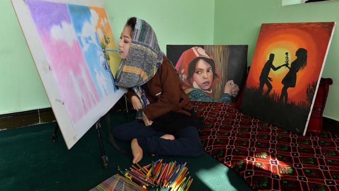 Seniman Robaba Mohammadi melukis dengan mulut di studionya di Kabul, 5 Desember 2019. Karya-karya Robaba telah dijual dan dipamerkan secara internasional dimana hasil penjualan lukisan membuatnya dapat meluncurkan pusat khusus untuk membantu melatih seniman difabel lainnya. (NOORULLAH SHIRZADA/AFP)