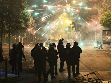 Polisi berdiri di tengah petasan pada malam ketiga protes yang dipicu oleh penembakan fatal polisi terhadap seorang pengemudi berusia 17 tahun di pinggiran Paris Nanterre, Prancis, Jumat, 30 Juni 2023. (AP Photo/Aurelien Morissard)