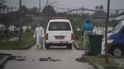 Sebuah mobil van membawa jenazah korban virus Corona Covid-19 untuk dimakamkan di tengah hujan lebat di pemakaman Keputih, Surabaya (7/1/2020). Pemerintah Kota Surabaya menyediakan tempat di TPU Keputih dan TPU Babat Jerawat untuk lahan pemakaman korban Covid-19. (AFP/Juni Kriswanto)