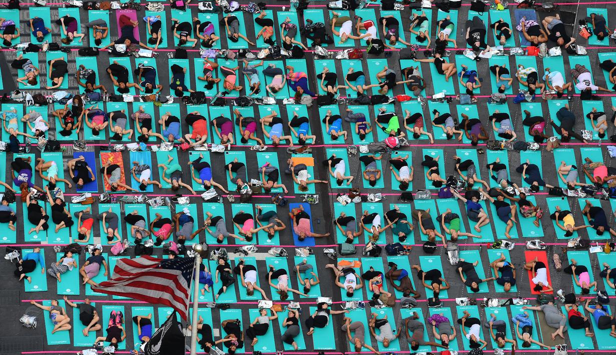 Warga berlatih yoga di tengah jalan Times Square, New York pada 'Summer Solstice' atau hari dengan siang terpanjang di musim panas, Rabu (21/6). Acara tersebut menandai Hari Yoga Internasional yang jatuh pada 21 Juni. (TIMOTHY A. CLARY/AFP)