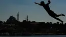Berlatar belakang Masjid Suleymaniye yang bersejarah, seorang pemuda melompat ke Tanduk Emas (golden horn) mengarah ke Selat Bosphorus yang memisahkan Eropa dan Asia, di Istanbul, Turki pada 3 Juli 2020. (AP Photo/Emrah Gurel)