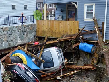 Warga berkumpul untuk melihat sejumlah mobil yang tersangkut di sebuah jembatan di Ellicott City, Maryland, Amerika Serikat, Senin (28/5). Banjir bandang Maryland diakibatkan meluapnya Sungai Patapsco. (AP Photo/David McFadden)