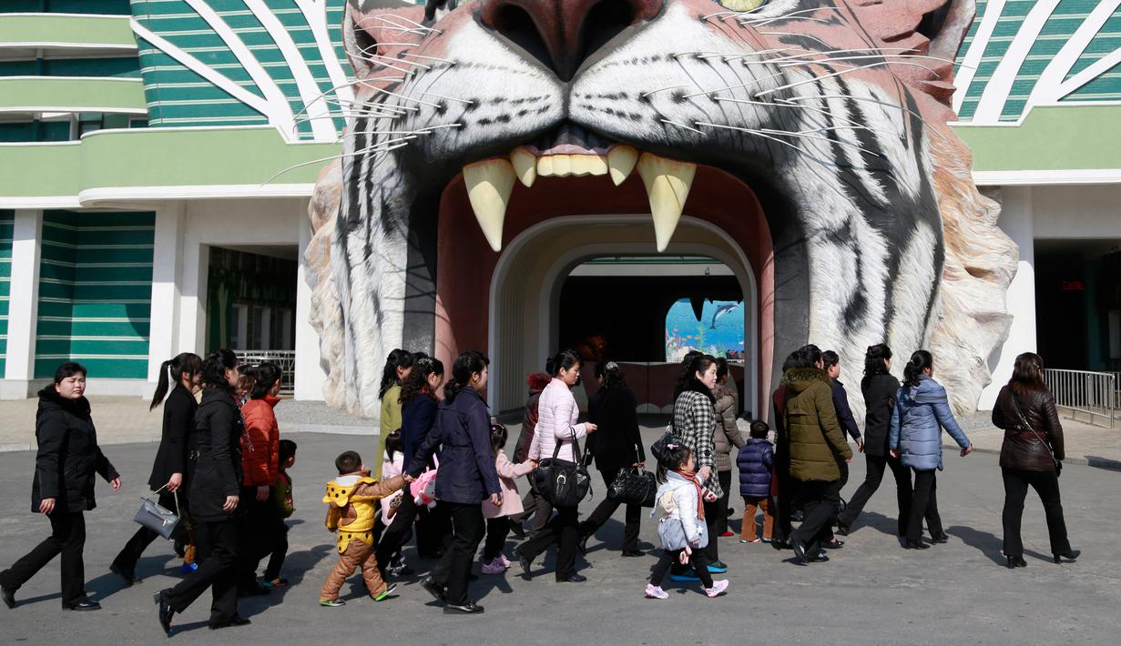 Sejumlah wanita berjalan melewati gerbang Kebun Binatang Pusat Korea saat perayaan Hari Perempuan Internasional di Pyongyang, Korea Utara, Jumat (8/3). (AP Photo/Dita Alangkara)
