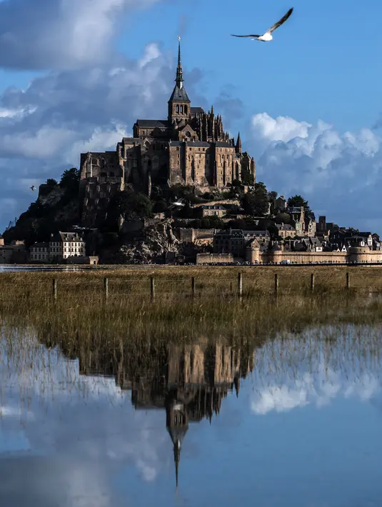 Kastil Mont Saint-Michel terlihat di Normandia, Prancis barat laut (1/9/2019). Dahulu Mont Saint Michel awalnya terhubung dengan daratan utama melalui sebuah jembatan kecil. Namun pada saat pasang jembatan tersebut tertutup dan terlihat pada saat surut. (AFP Photo/Joel Saget)