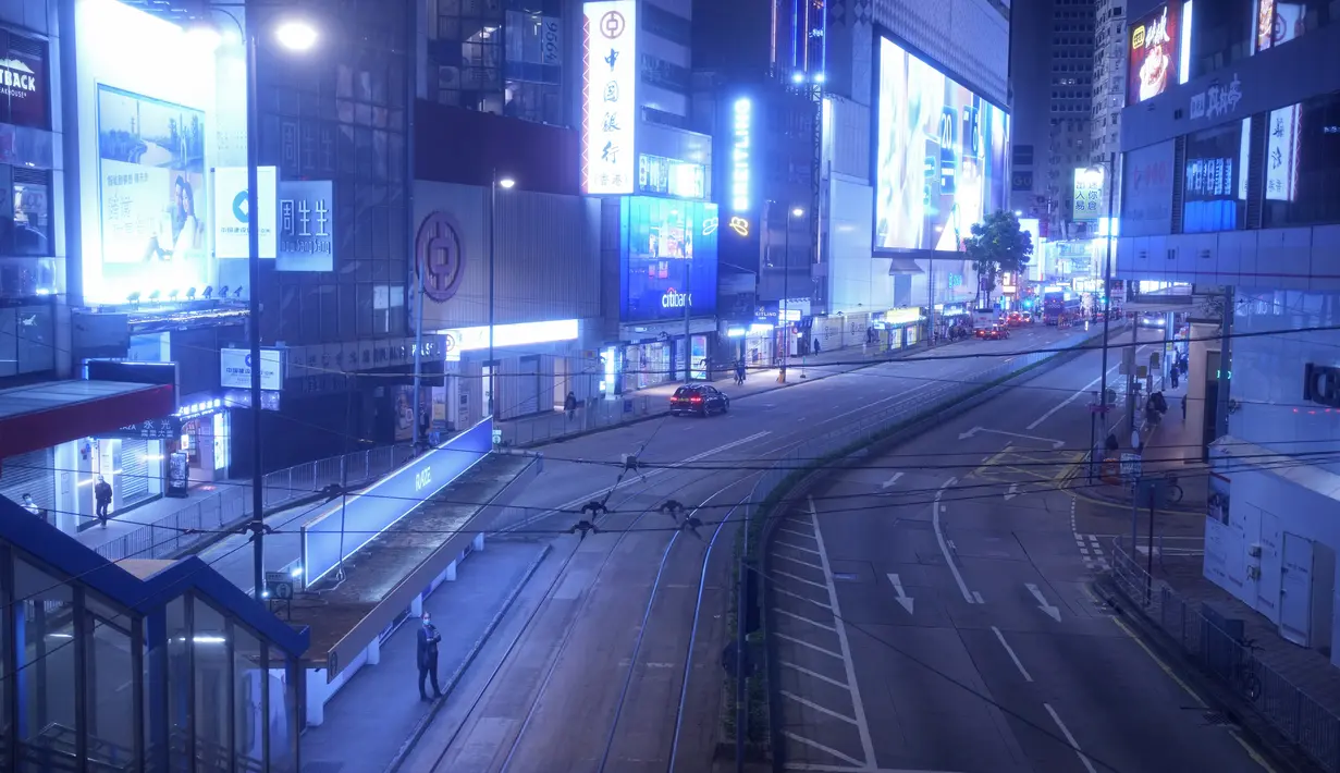 Seorang perempuan berdiri di jalan kosong yang biasanya dipenuhi pembeli di Causeway Bay, sebuah distrik perbelanjaan terkenal di Hong Kong pada 10 Maret 2022. Lampu neon Hong Kong masih menyala, tetapi COVID-19 telah mematikan banyak aktivitas kota yang biasa berenergi. (AP Photo/Vincent Yu)