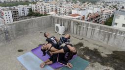 Instruktur yoga dari Zona Yoga Anahata melakukan gerakan yoga menjelang Hari Yoga Internasional di teras sebuah bangunan di Hyderabad, India pada 18 Juni 2020. Hari Yoga Internasional atau International Day of Yoga diperingati setiap tahun pada 21 Juni. (Photo by NOAH SEELAM / AFP)