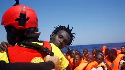 Seorang imigran diselamatkan dari perahu kayu yang disesaki ratusan imigran, di lepas panti Libya, Laut Mediterania, Senin (29/8). Para penjaga pantai Italia berhasil menyelamatkan sekitar 6.500 imigran dari Eritrea dan Somalia. (REUTERS/Giorgos Moutafis)
