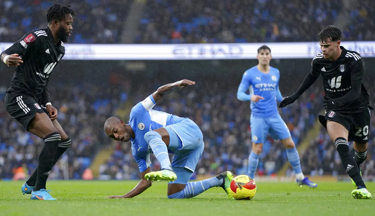 Pemain Manchester City Fernandinho jatuh ke tanah antara pemain Fulham Nathaniel Chalobah (kiri) dan Neco Williams (kanan) pada pertandingan sepak bola putaran keempat Piala FA di Etihad Stadium, Manchester, Inggris, 5 Februari 2022. Manchester City menang 4-1. (AP Photo/Jon Super)